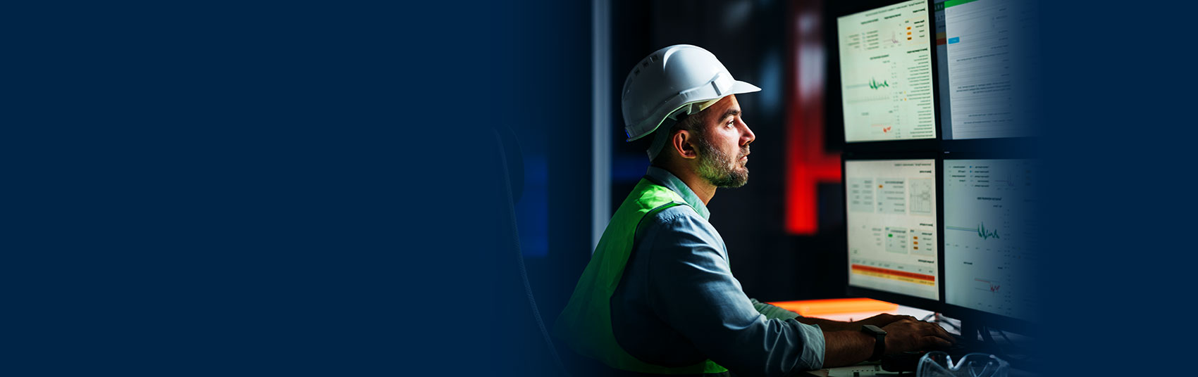 field manager in hard hat looking at dashboards on computer screens