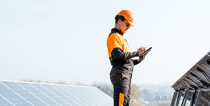 Field worker using tablet to inspect solar panels